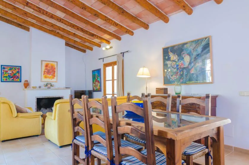 A dining area with a wooden table and chairs beneath exposed ceiling beams.