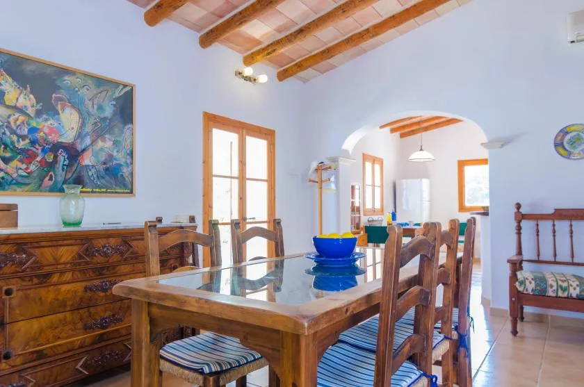 A dining room with a wooden table, chairs, and colorful wall art.