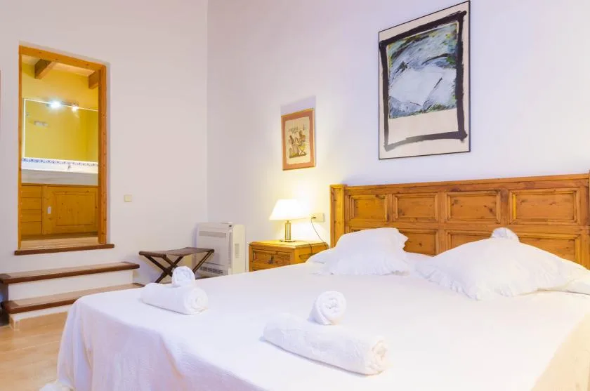 A bedroom with a bed, wooden headboard, and framed artwork.