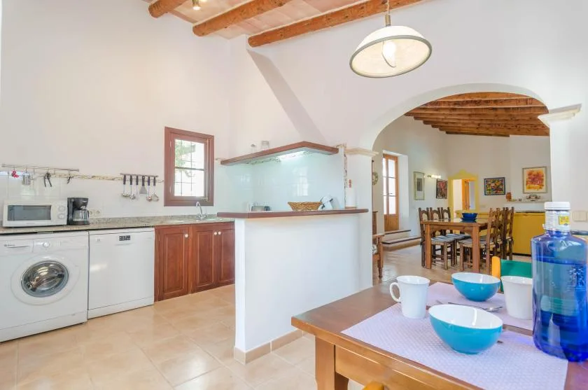 A kitchen and dining area with a counter, table, and exposed wooden ceiling beams.