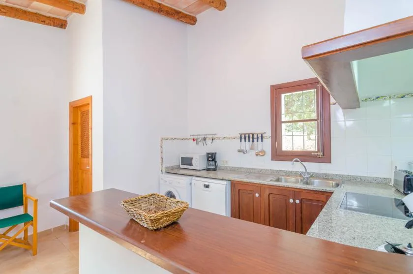 A bright kitchen with a wooden counter, cabinets, and a window.