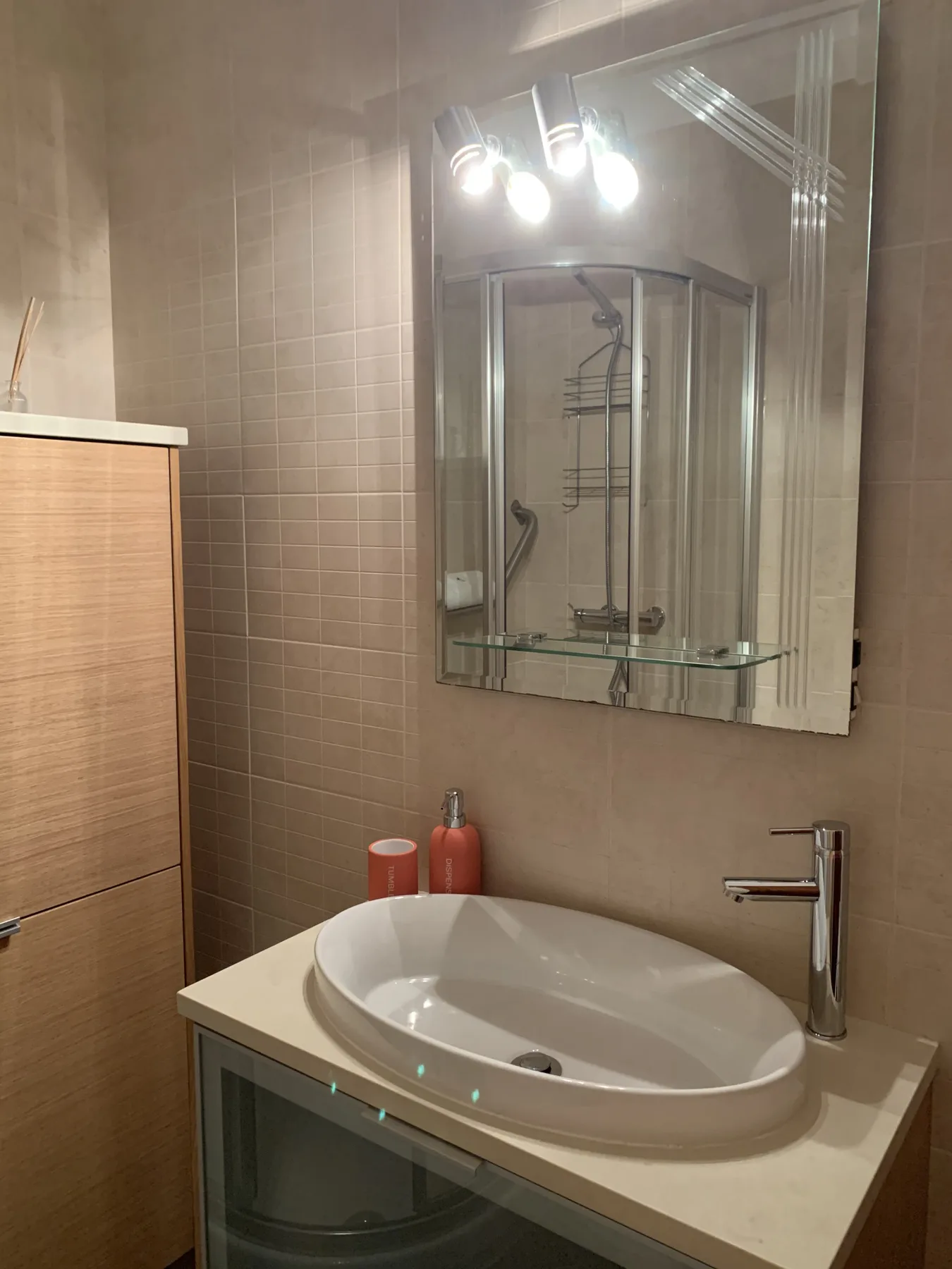 A bathroom vanity with an oval sink and a mirrored cabinet.