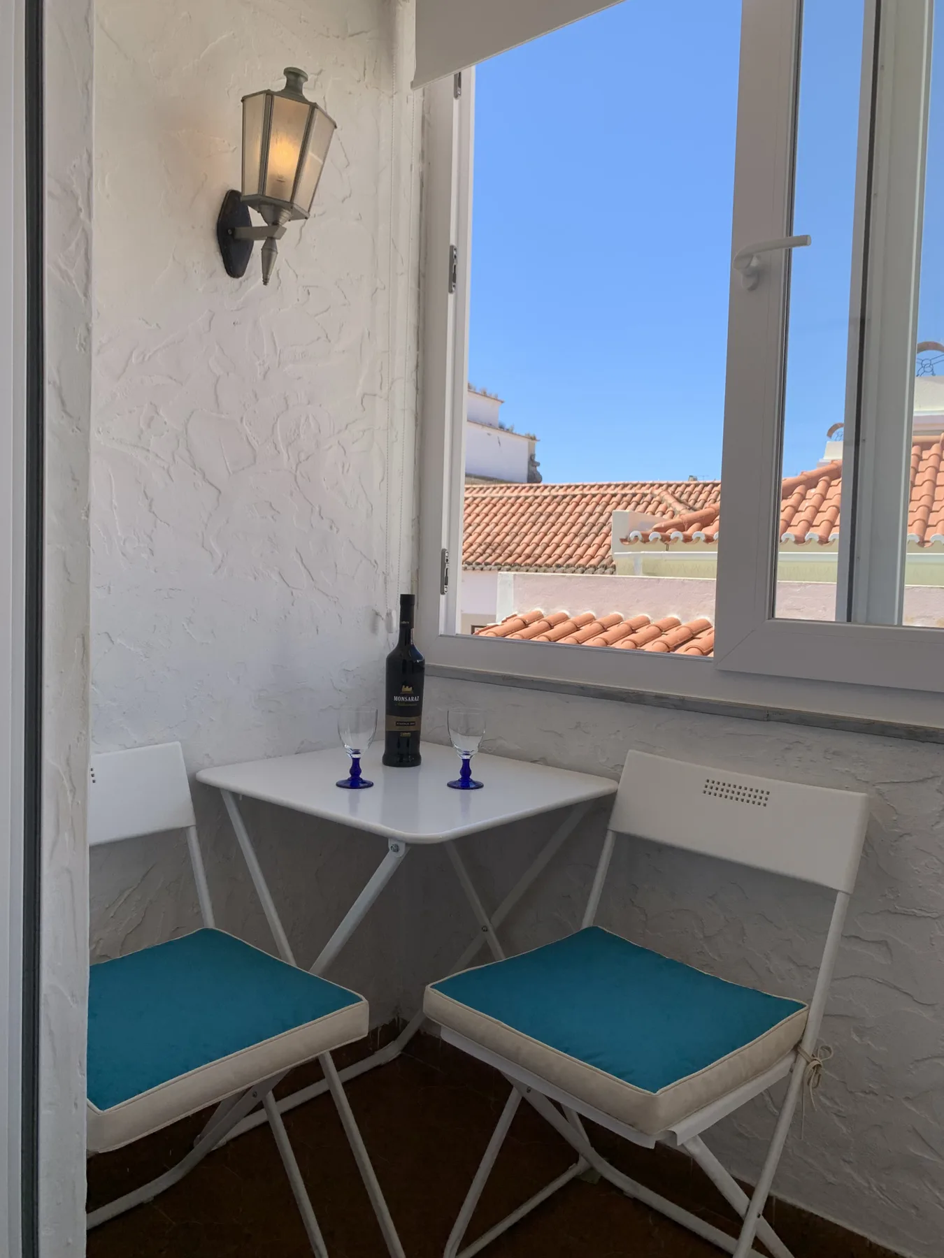 A small window-side seating nook with two chairs and a view of tiled rooftops.
