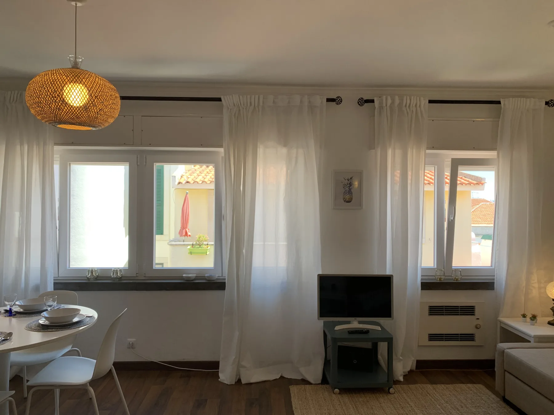 Living area with a television, dining table, and curtained windows.