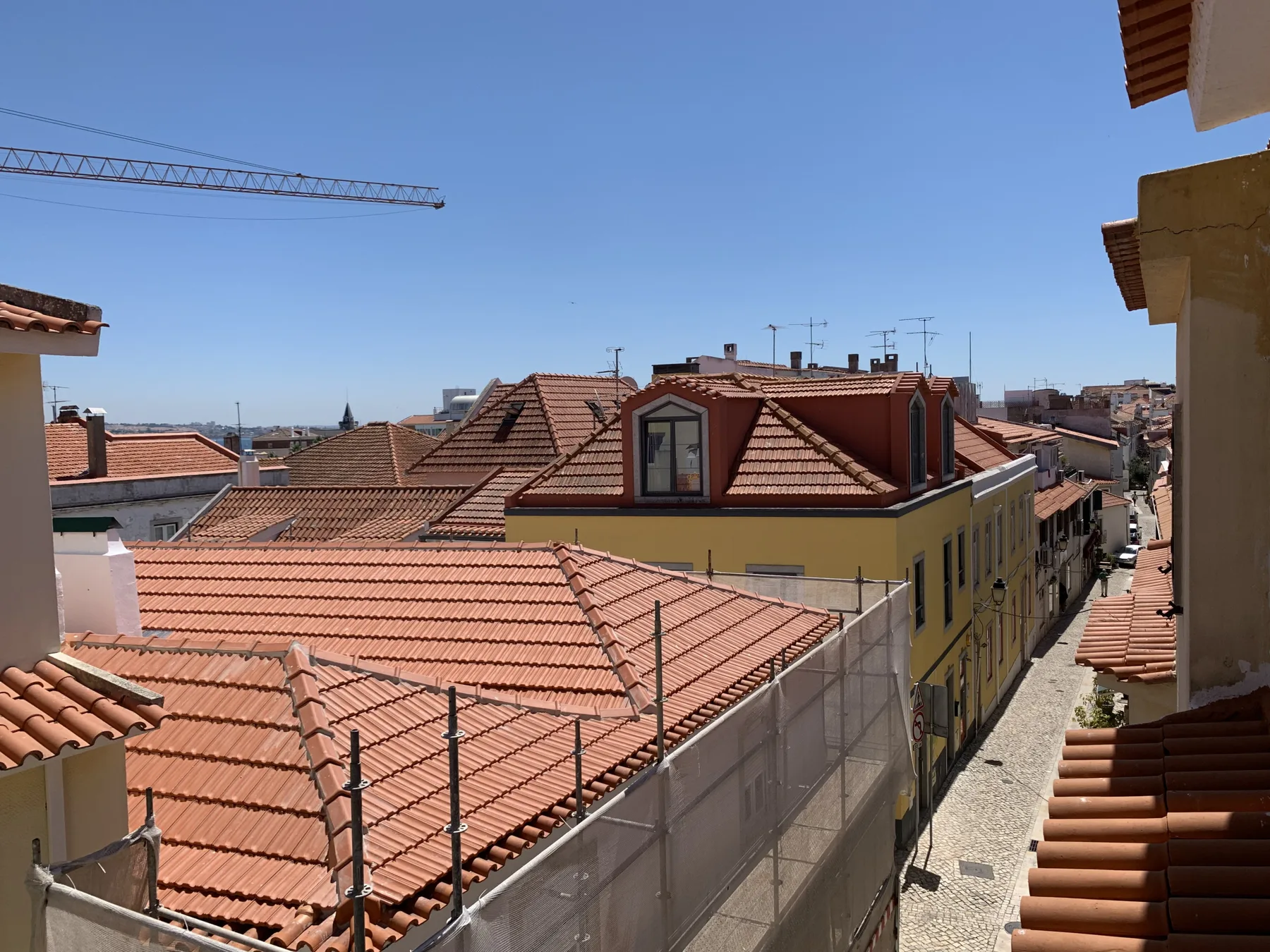 A view over a city street and surrounding red-tiled rooftops.