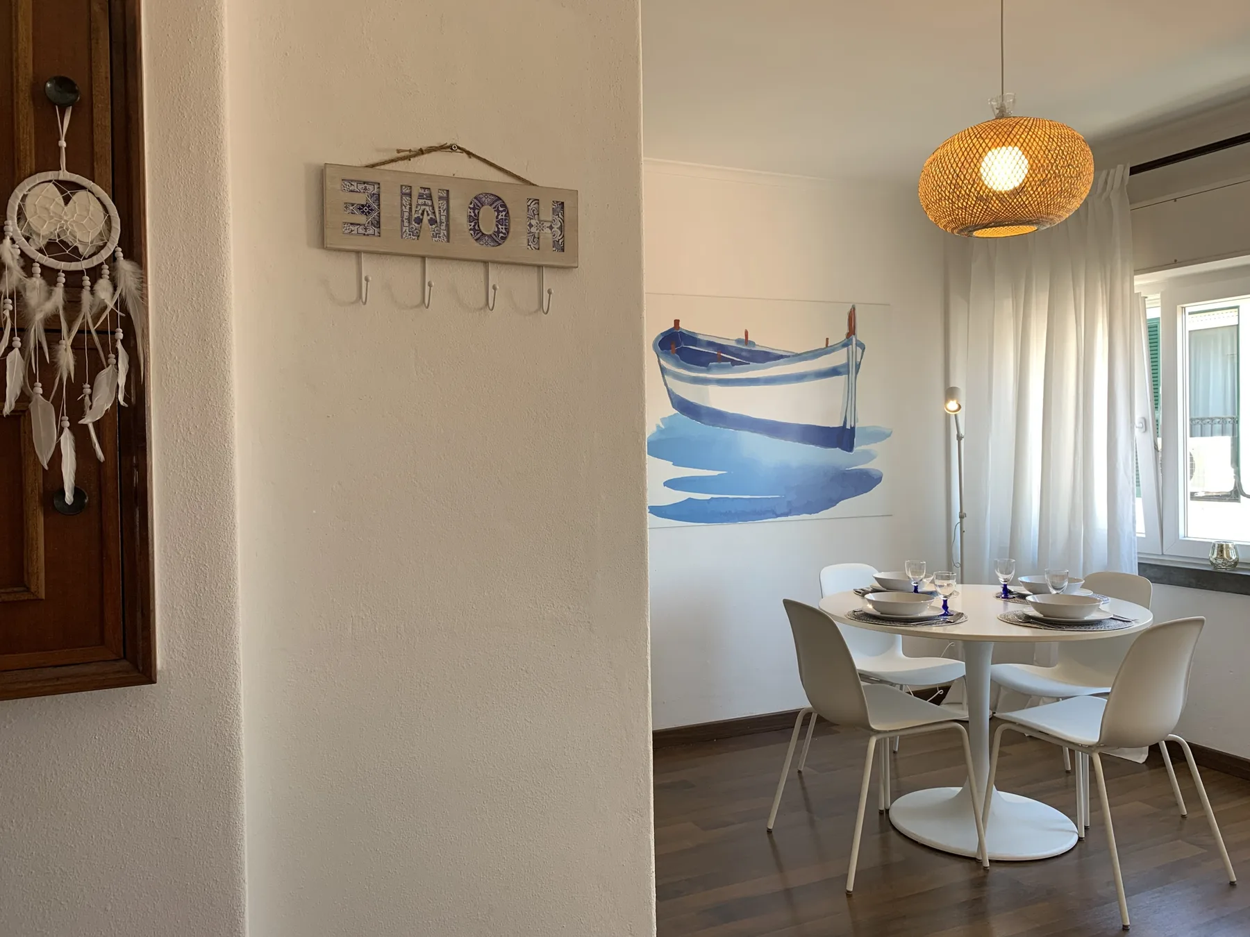 A dining area with a round table sits beside a wall mural of a boat.