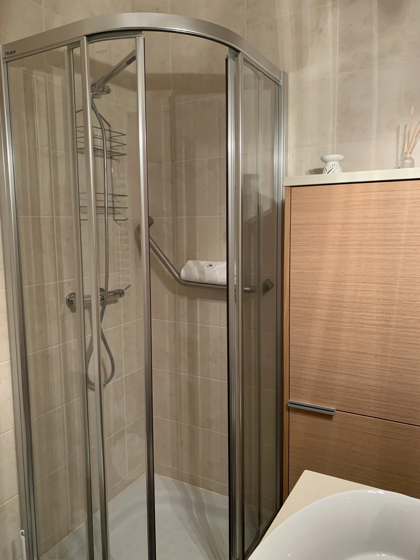 A tiled bathroom with a glass shower and a sink.