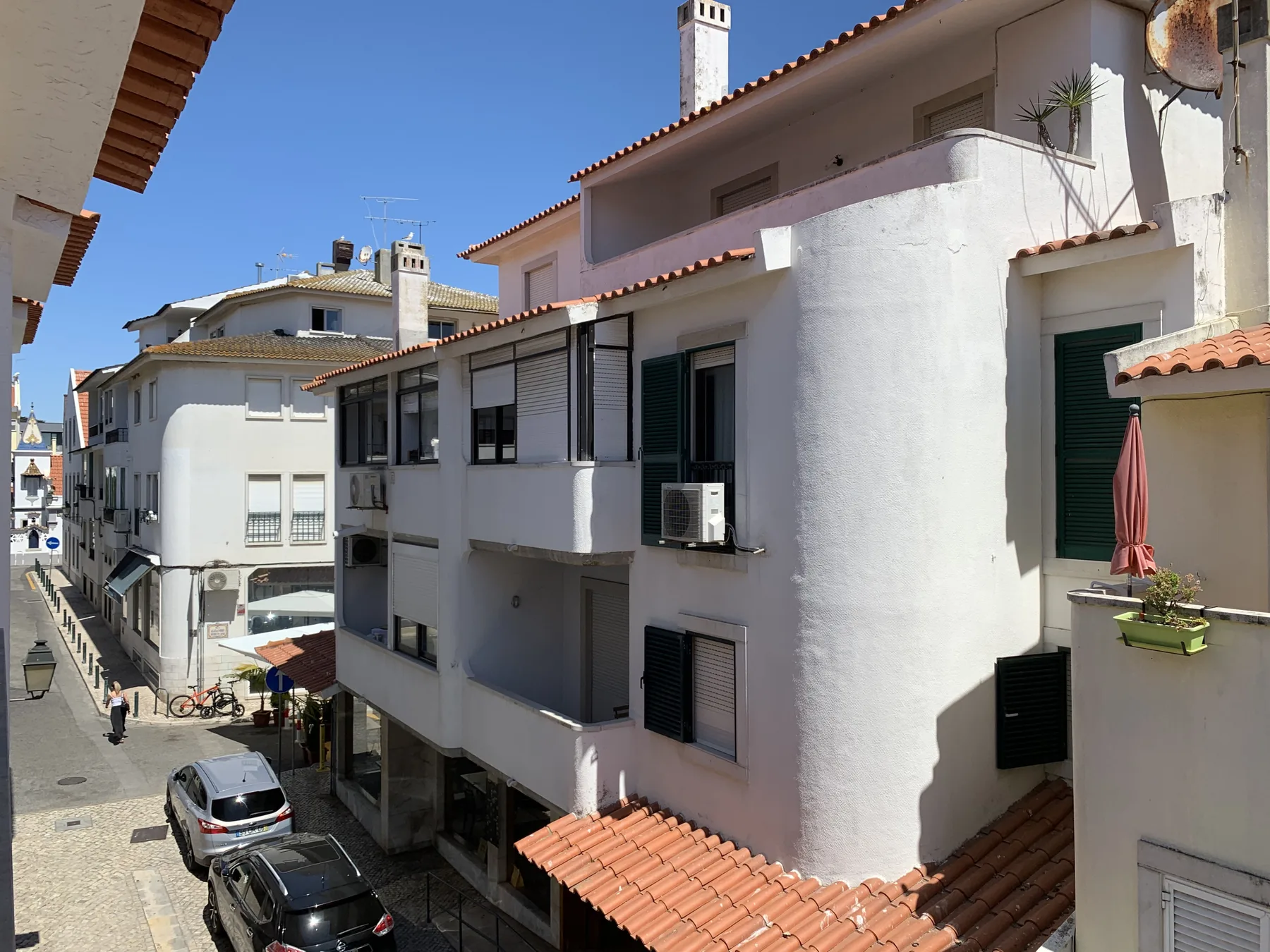 A narrow street lined with white buildings and red-tiled roofs.