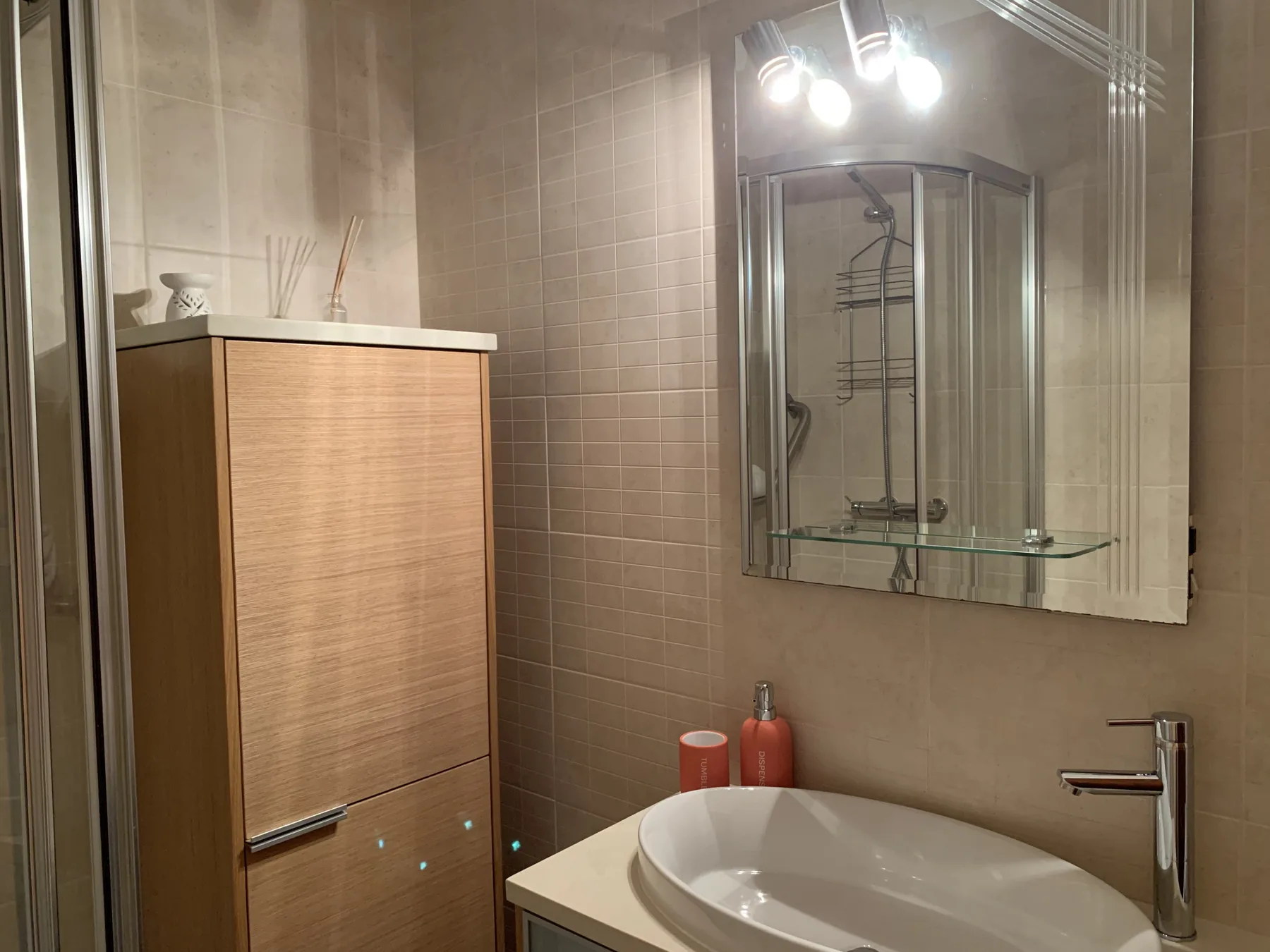 A tiled bathroom with a sink, mirror, and wooden cabinet.