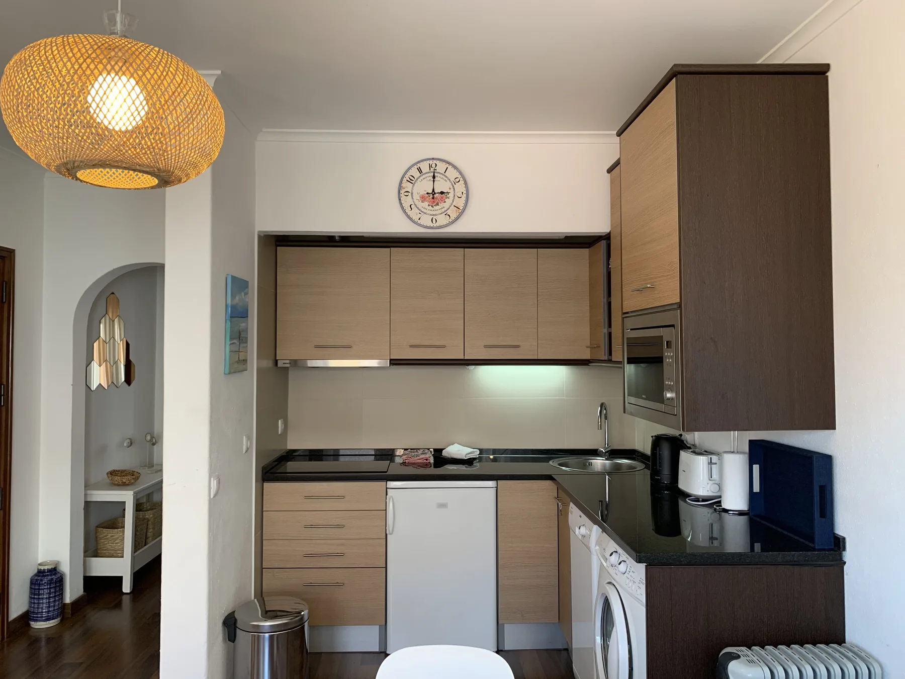 A compact kitchen with wooden cabinets, a countertop, and built-in appliances.