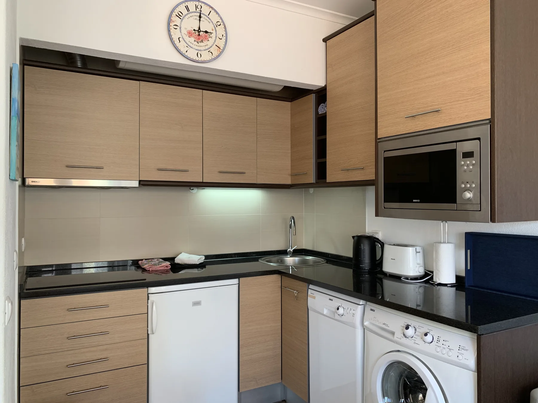 A compact kitchen with wood-toned cabinets and countertop appliances.