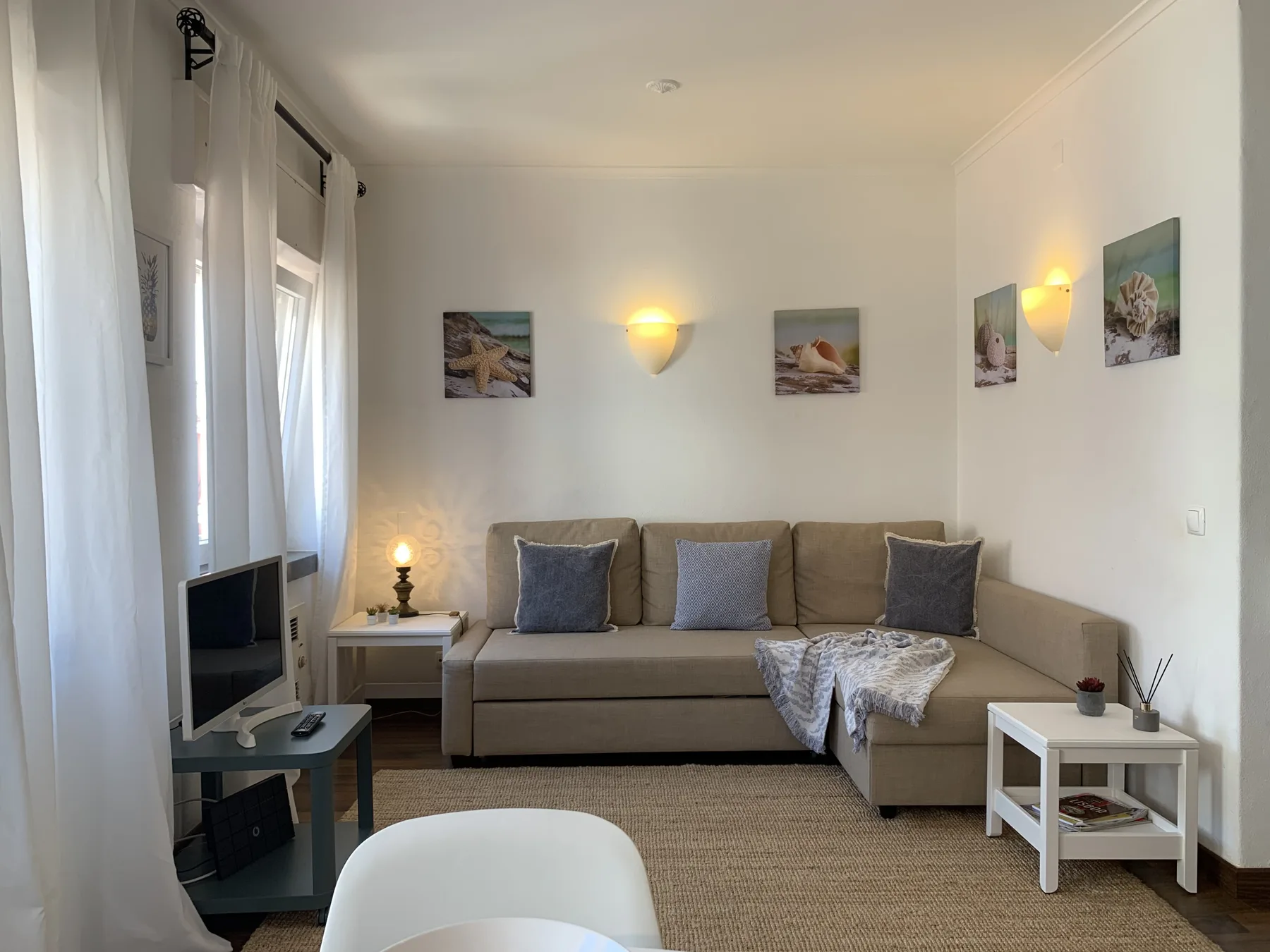 A living room with a sectional sofa, television, and wall art.