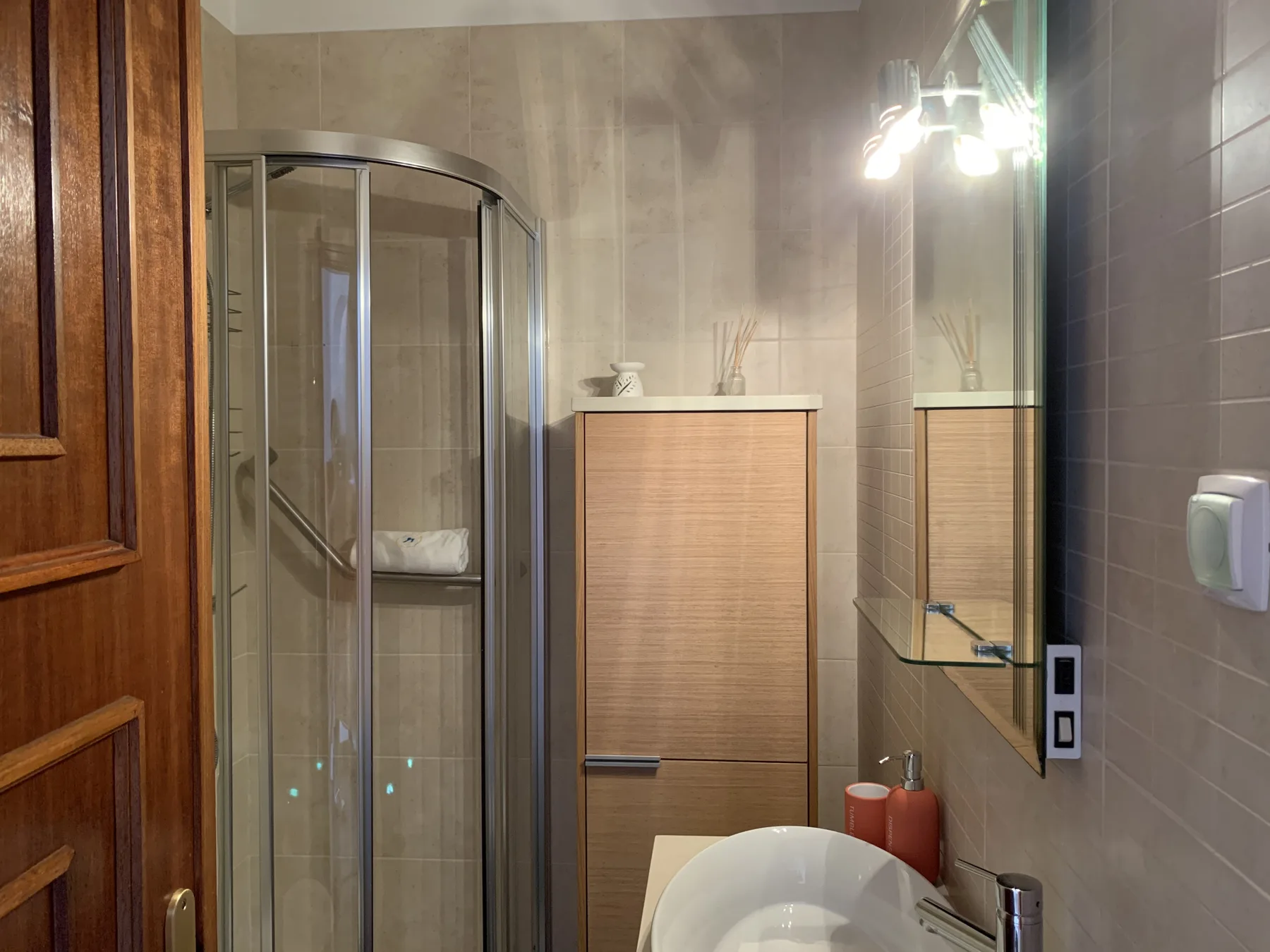 A tiled bathroom with a glass shower and a white sink.
