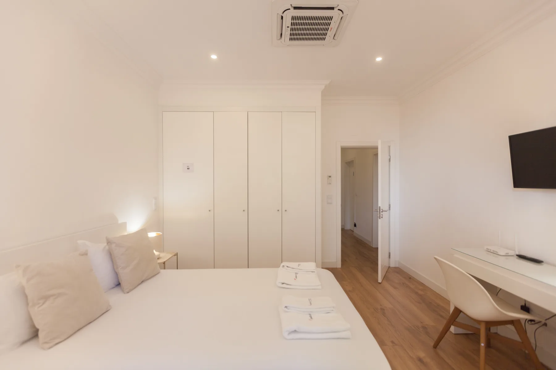 A bright bedroom with a bed, built-in cabinets, and a desk.