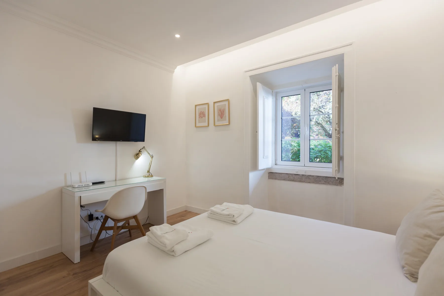 A bright bedroom with a bed, desk, and window.