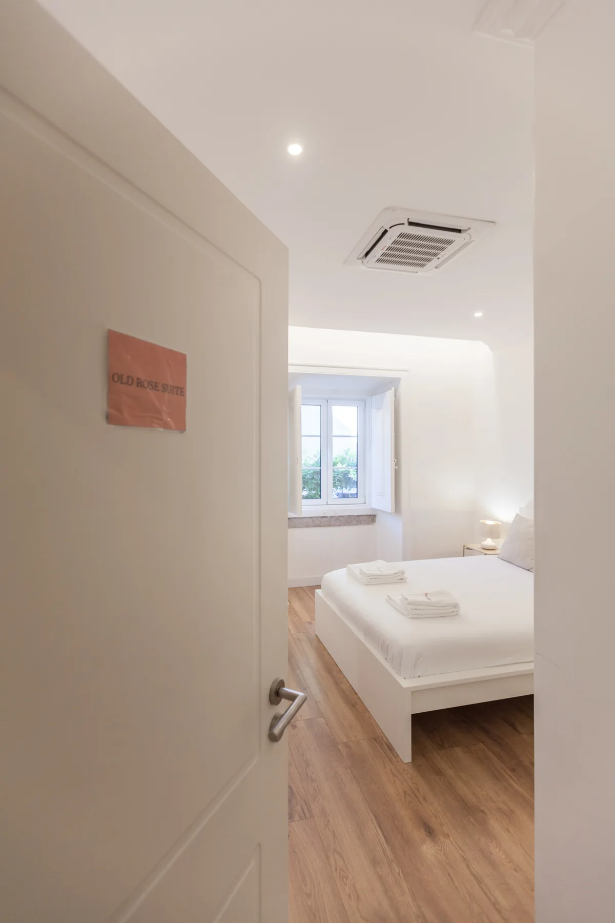 A bright bedroom with a bed and a window at the far end.