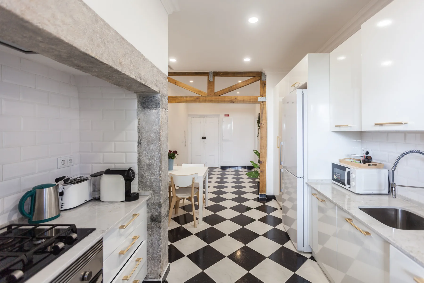 A bright kitchen with white cabinets and a black-and-white checkerboard floor.