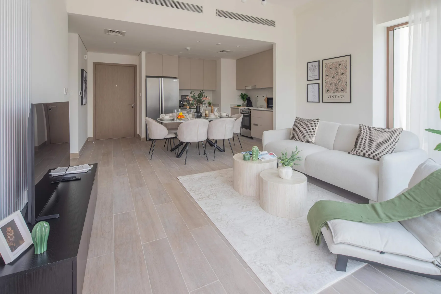 Un salón de planta abierta con cocina, mesa de comedor y asientos claros.