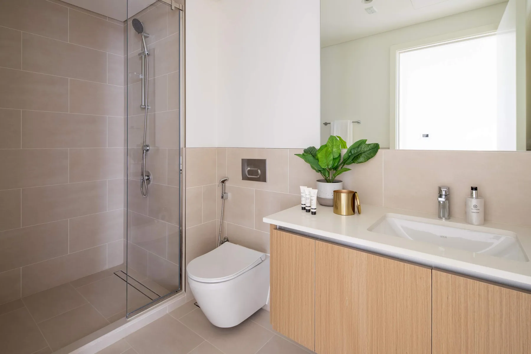 Un baño luminoso con ducha, inodoro y lavabo.