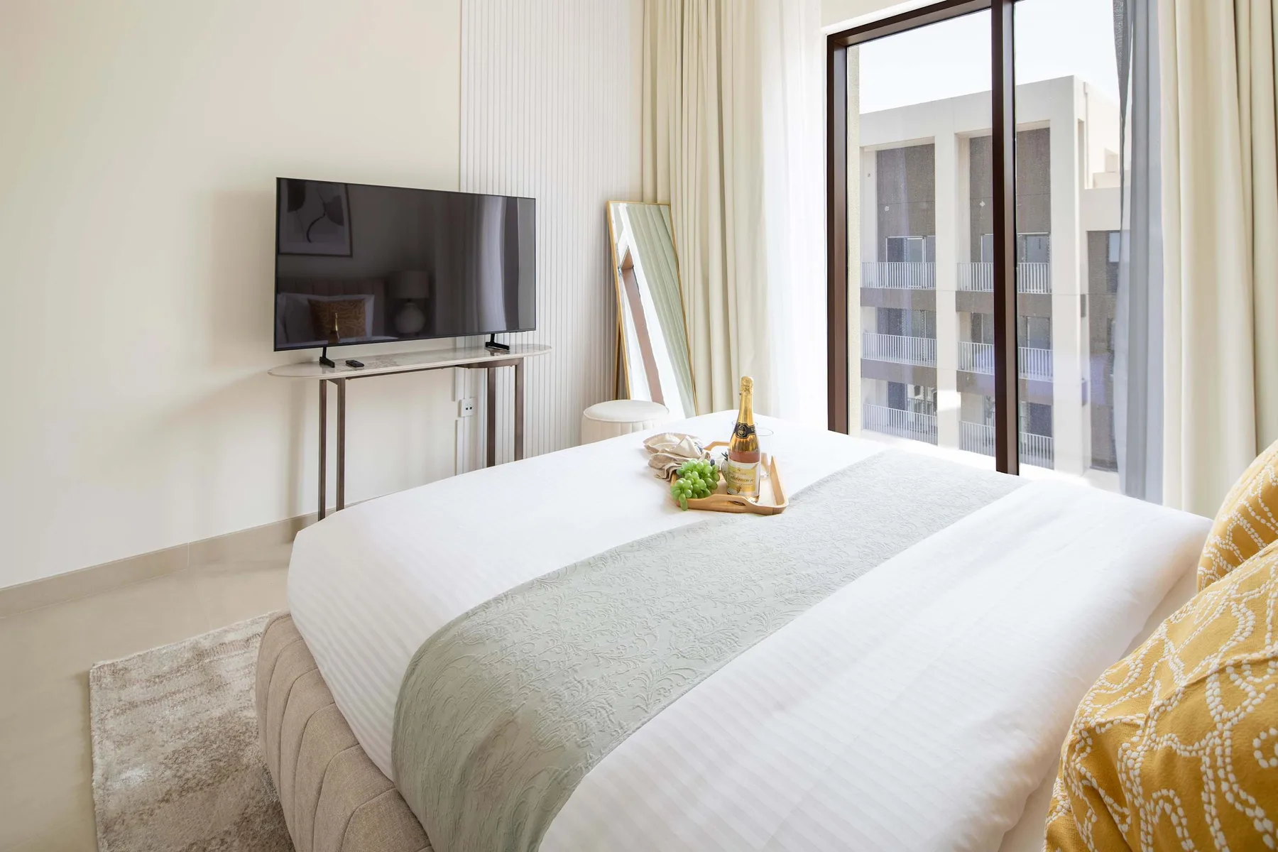 Un dormitorio luminoso con una cama bien hecha junto a una ventana grande.