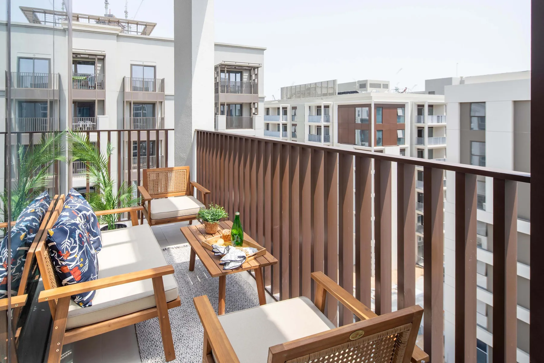 Un balcón amueblado con asientos, una mesa pequeña y vistas a edificios cercanos.