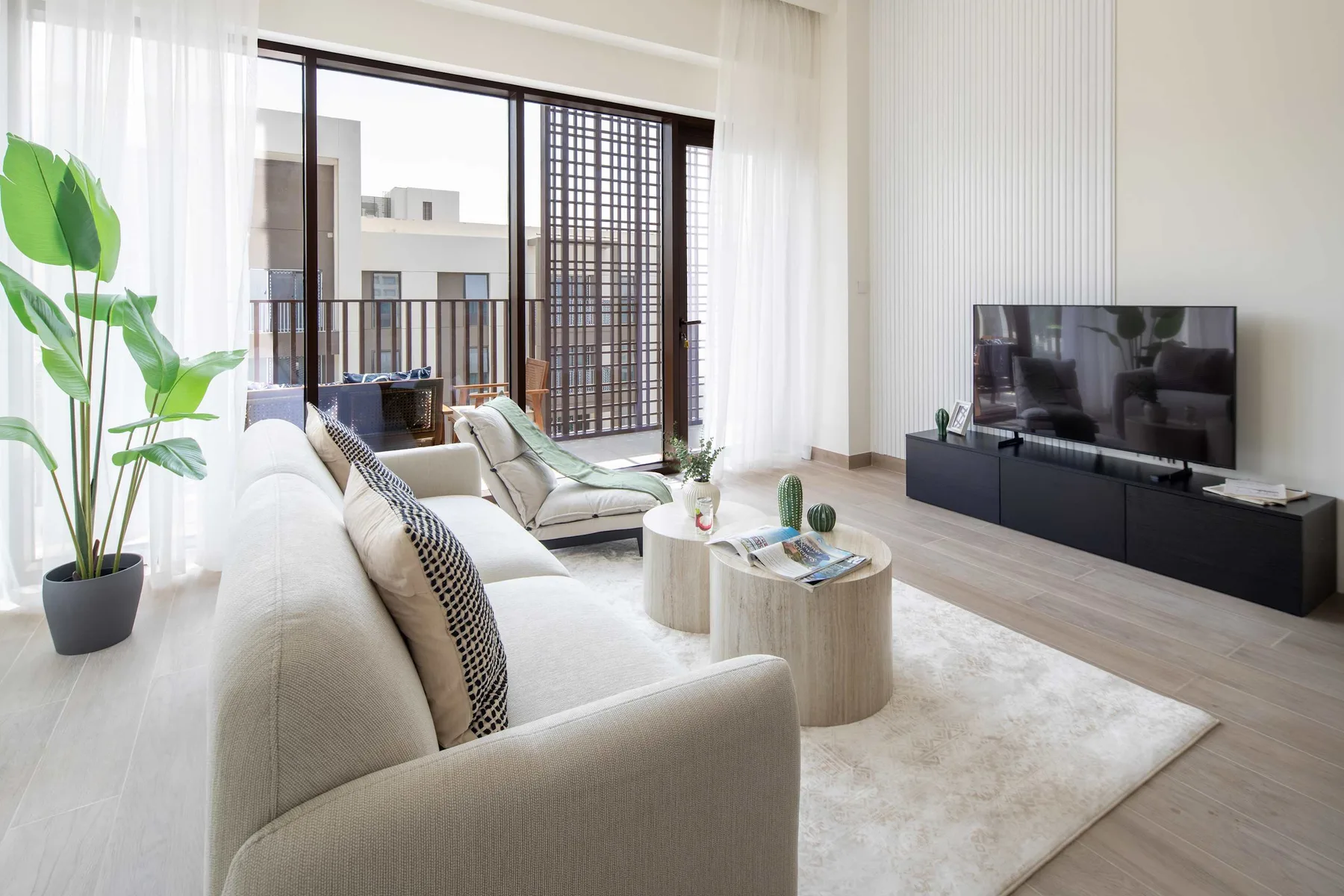 Sala de estar luminosa con asientos, una mesa de centro y un televisor.