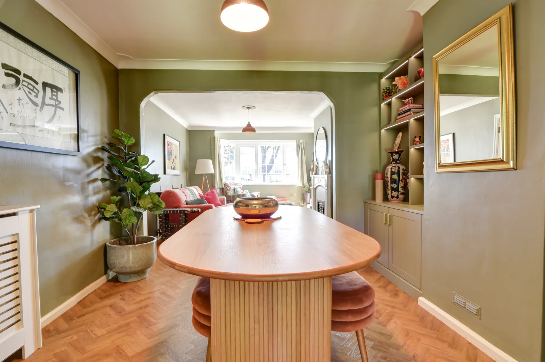 A dining area with a long wooden table and built-in shelves.