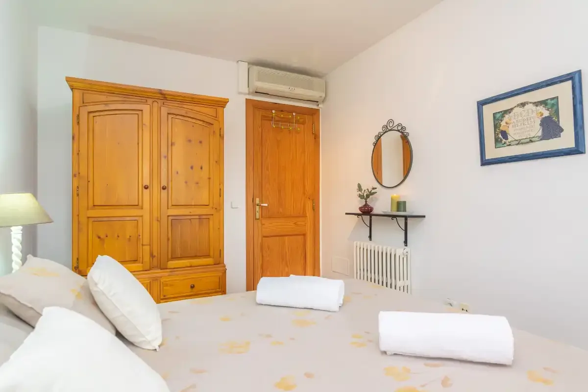 Un dormitorio con una cama, un armario de madera y una puerta.