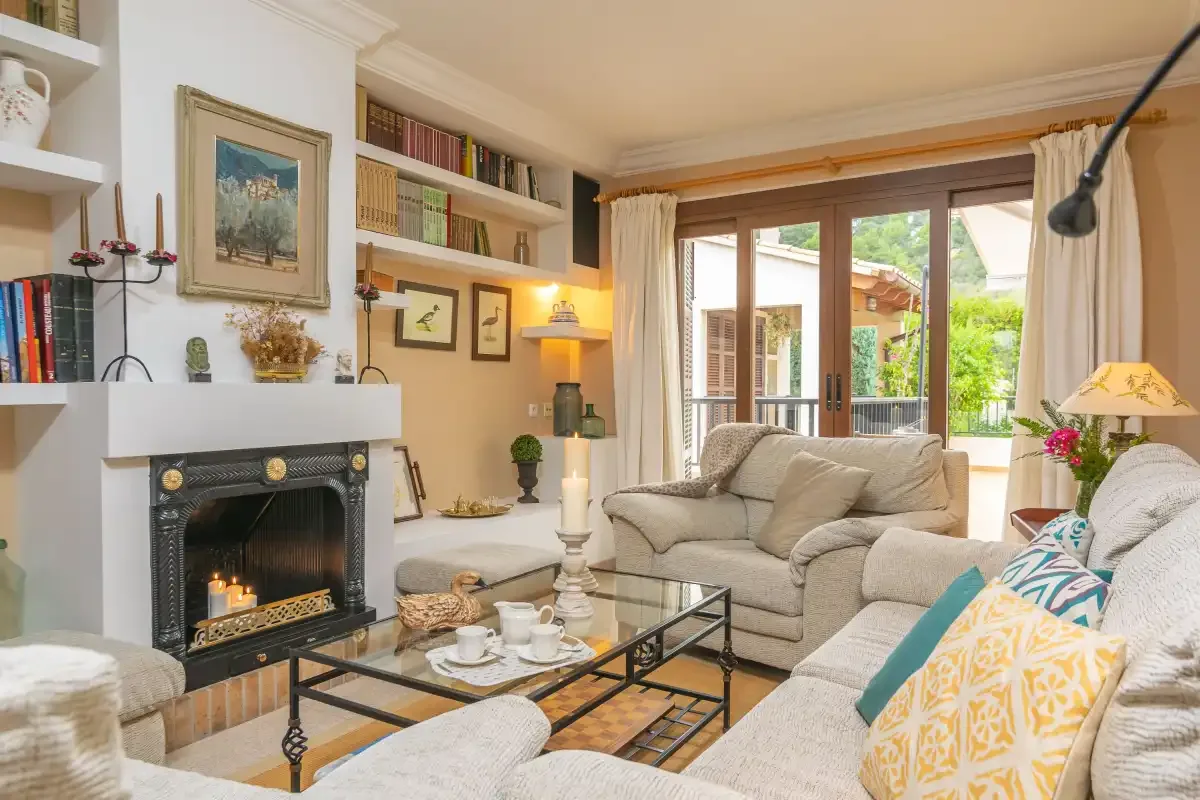 Una sala de estar con asientos, chimenea y puertas de cristal que dan a un jardín.
