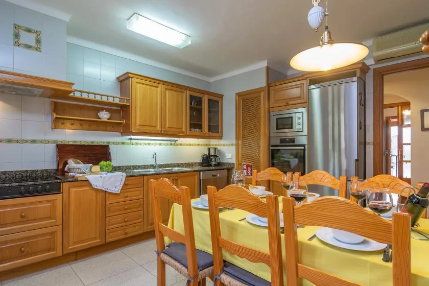 Una cocina y comedor con armarios de madera y una mesa puesta con vajilla.
