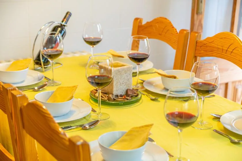 Una mesa de comedor está puesta con platos, copas de vino y un centro de mesa.