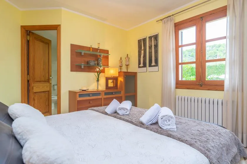 Un dormitorio con una cama, muebles de madera y una ventana con vistas a la vegetación.