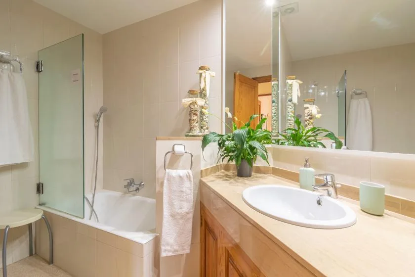 Un baño con bañera, mampara de vidrio y lavabo con mueble.