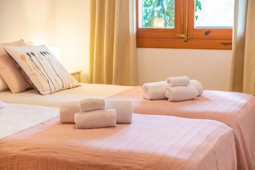 Un dormitorio con dos camas, toallas dobladas y una ventana.