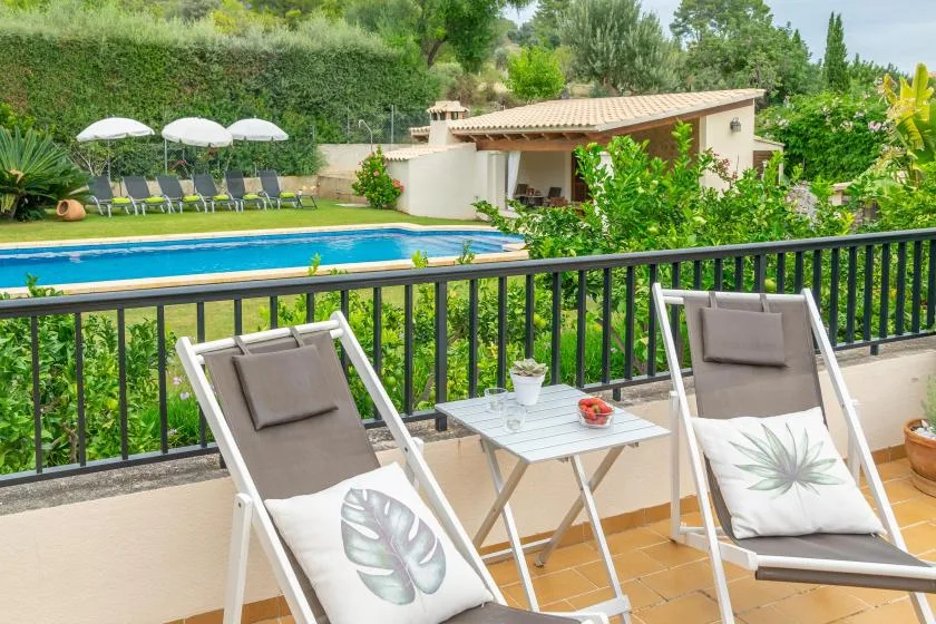 Una zona de estar en el patio da a una piscina y un jardín ajardinado.