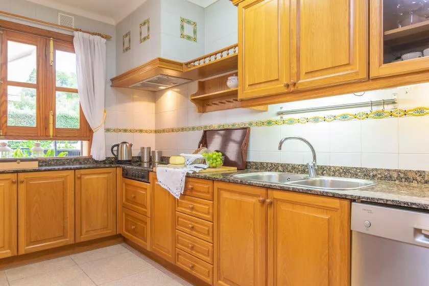Una cocina luminosa con armarios de madera, una encimera y un fregadero.