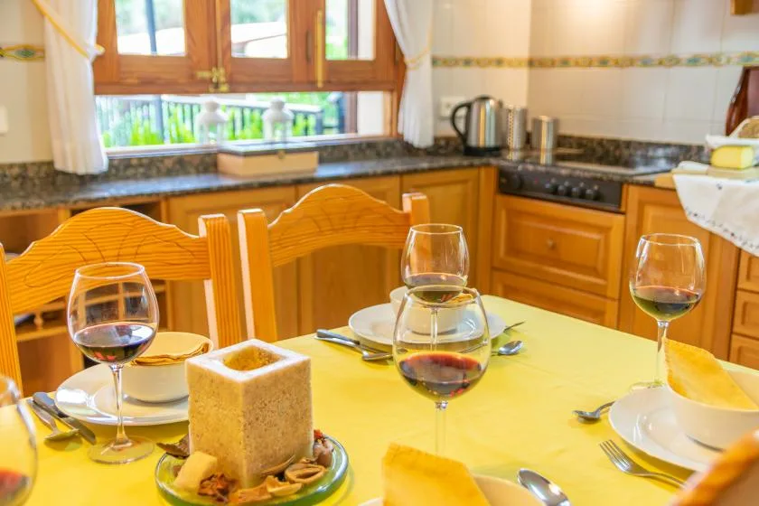 Una mesa puesta con platos y copas está frente a una cocina.
