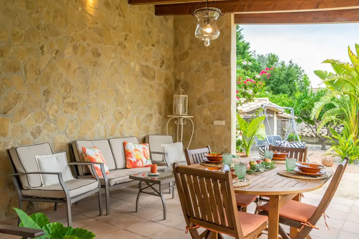 Un patio cubierto con asientos y una mesa de comedor da a un jardín frondoso.
