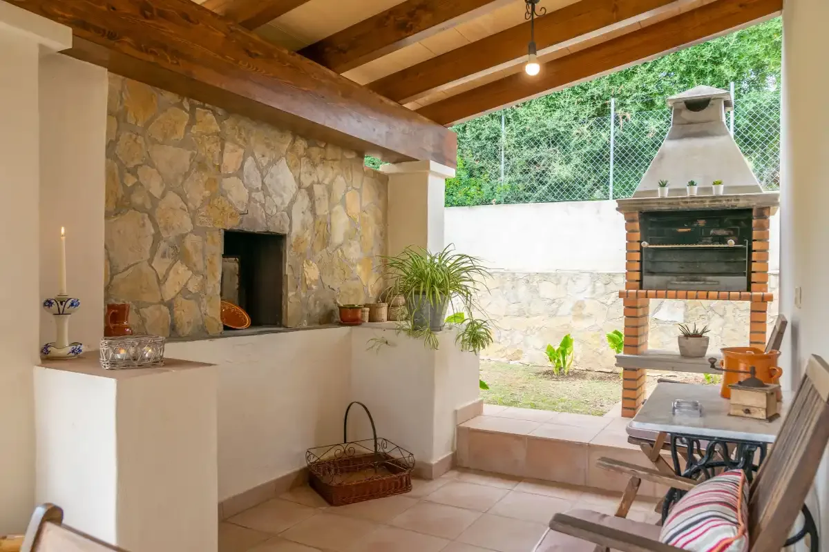 Un patio cubierto cuenta con una chimenea de piedra y una parrilla exterior.