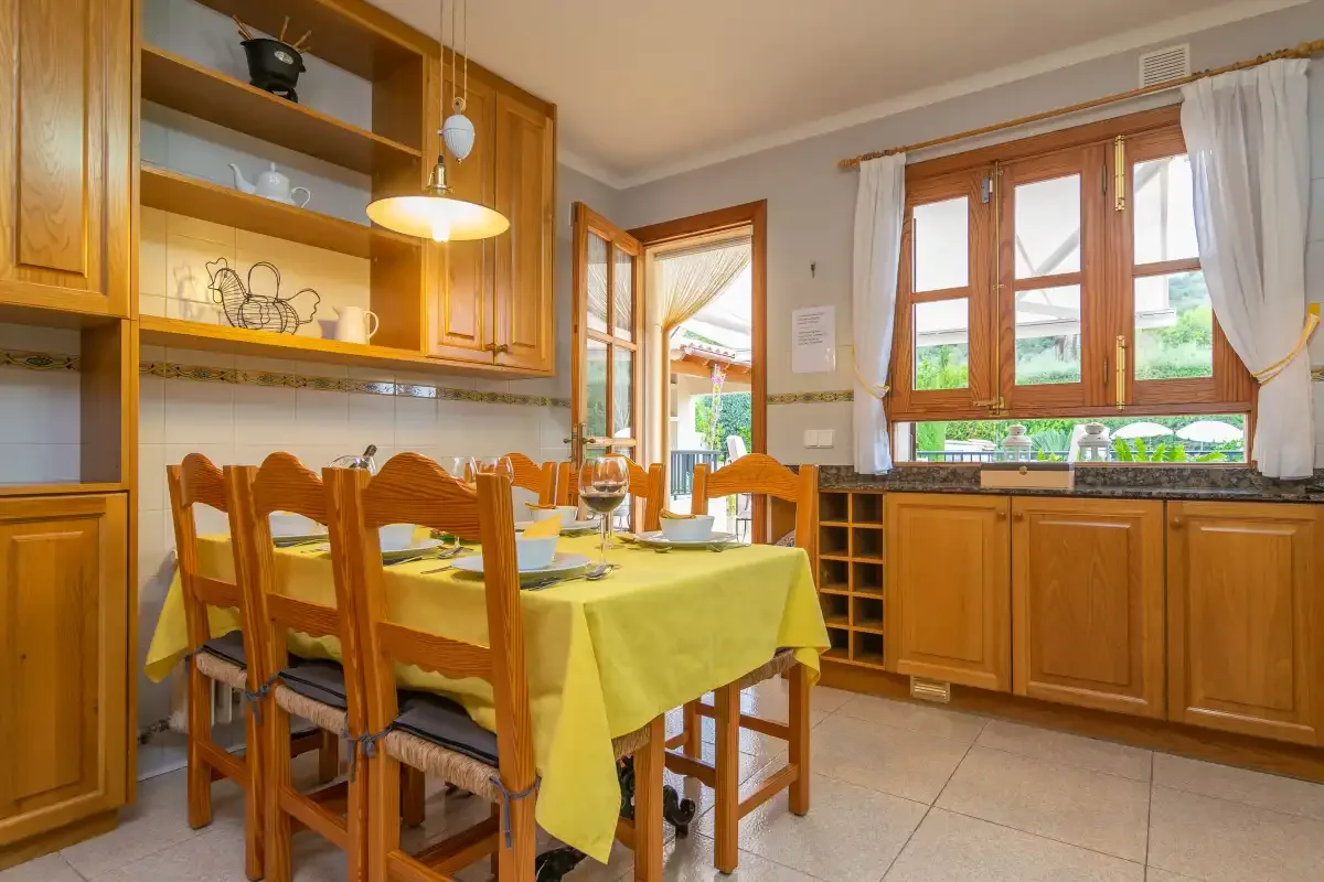 Comedor con asientos de madera y una mesa junto a una ventana luminosa.