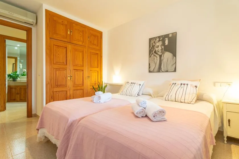 Un dormitorio con dos camas vestidas con ropa de cama rosa y un armario de madera.