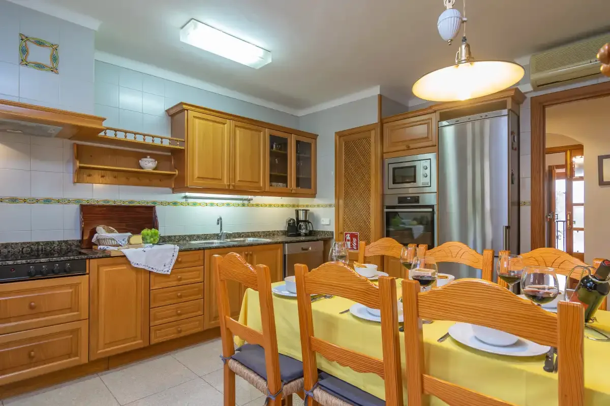 Una cocina y comedor con armarios de madera y una mesa puesta.