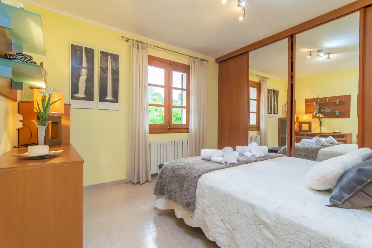 Dormitorio con una cama, toallas dobladas y puertas de armario con espejo.