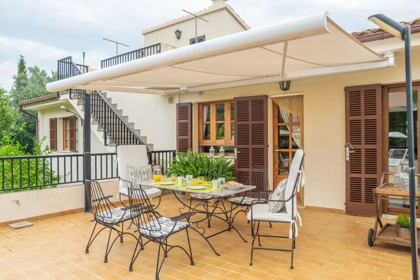 Una terraza exterior soleada con toldo retráctil y asientos de patio.