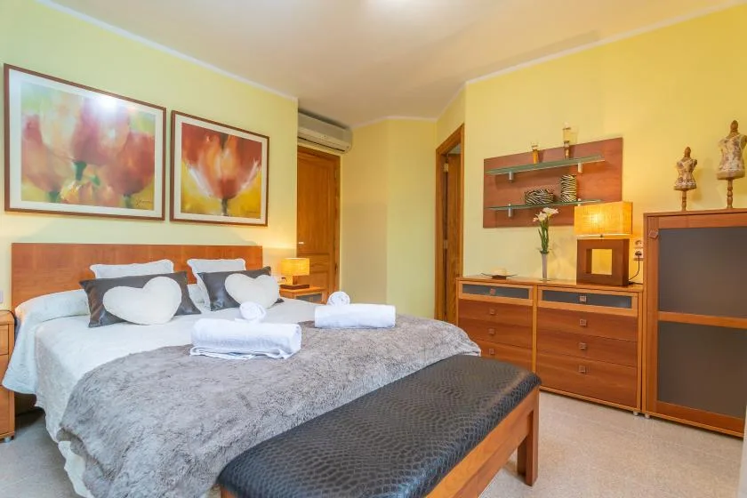 Un dormitorio con una cama doble, cuadros coloridos y muebles de madera.
