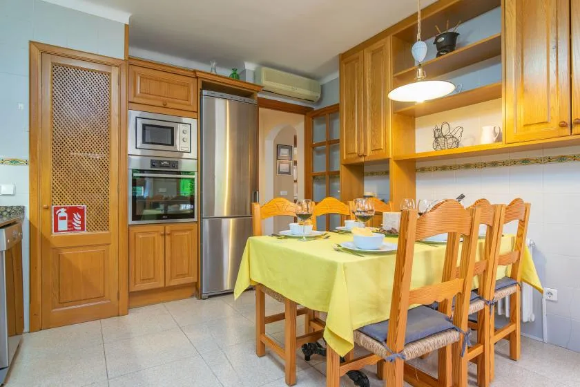 Comedor en una cocina con mantel amarillo y asientos de madera.