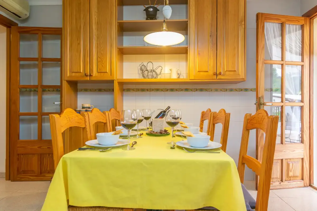 Un comedor con una mesa preparada para comer bajo armarios de madera.