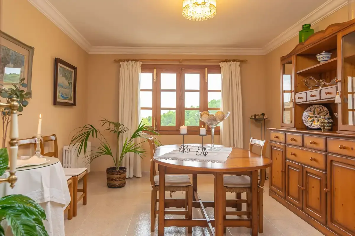 Un comedor con una mesa de madera, sillas y un gran aparador.