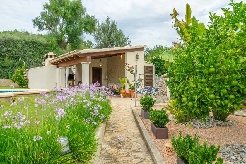 Un sendero de jardín conduce a un patio sombreado junto a una piscina.