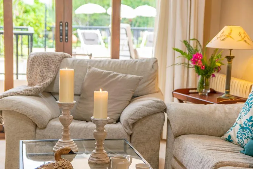 Una sala luminosa con asientos claros, velas y una mesa de centro de vidrio.